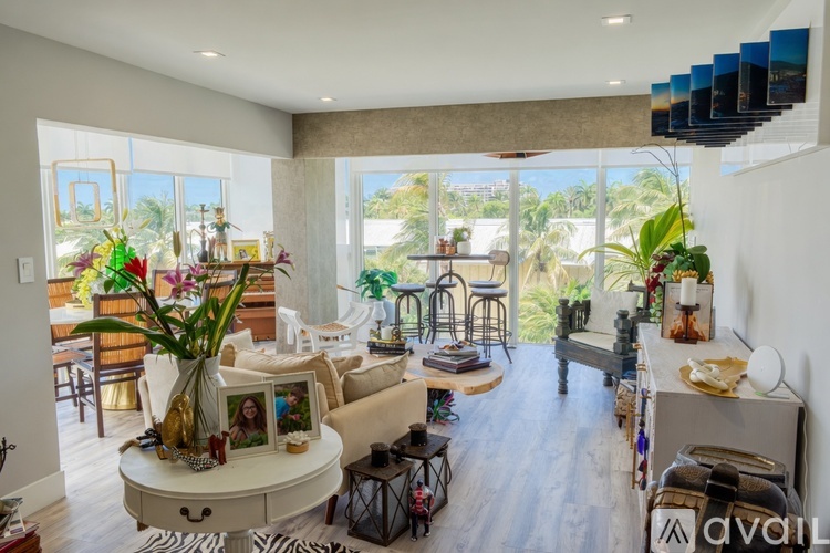 A living room with a white couch and a coffee table with a vase of flowers on it.