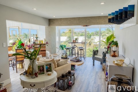 A living room with a white couch and a coffee table with a vase of flowers on it.