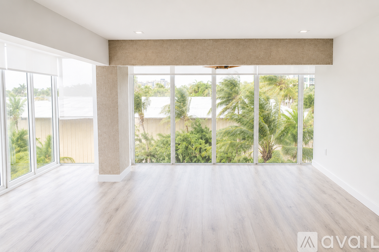 A spacious room with large windows overlooking a tropical landscape.