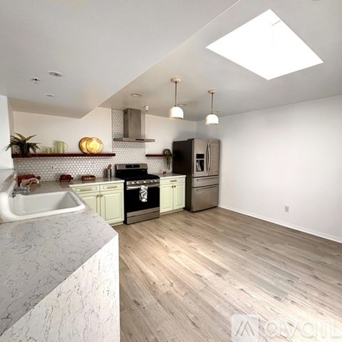 A kitchen with a white marble countertop and wooden flooring.