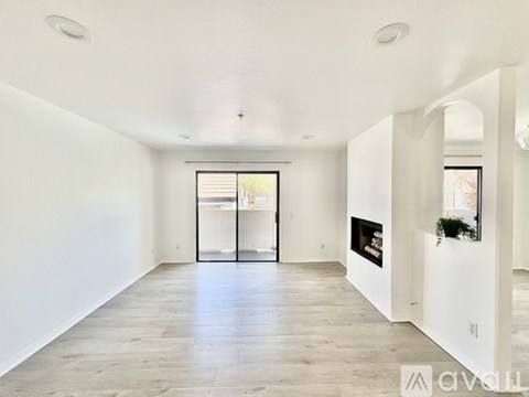 A spacious, empty room with a fireplace and a large window.