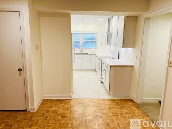 A kitchen with white cabinets and a wooden floor.