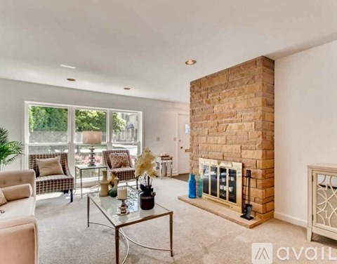 A living room with a glass coffee table and a brick fireplace.