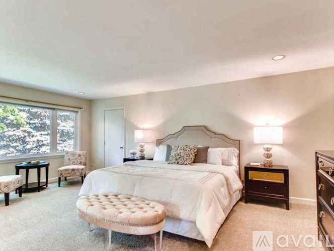 A bedroom with a large bed and a window with a view of trees.