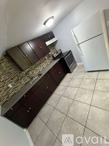 A kitchen with dark brown cabinets and a white refrigerator.