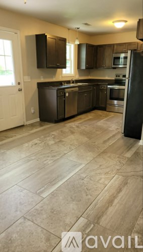 A kitchen with a tile floor and a black refrigerator.