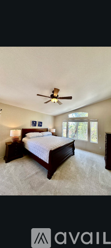 A bedroom with a large bed and a ceiling fan.
