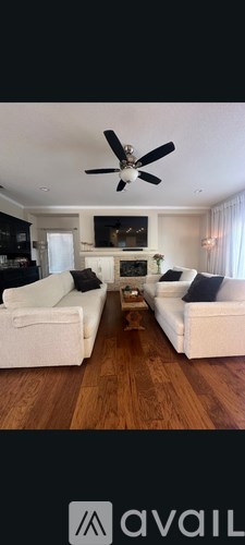 A living room with white furniture and a ceiling fan.