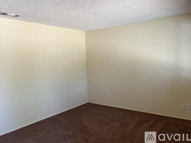 A room with a carpeted floor and a wall with a switch.