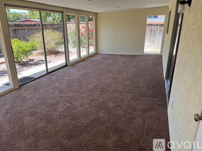 A room with carpeted floor and sliding glass doors.