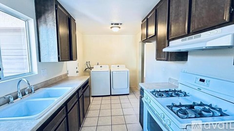 A kitchen with a stove, sink, and cabinets.