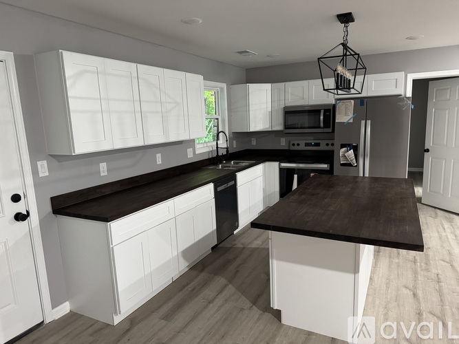 A modern kitchen with white cabinets and a dark countertop.