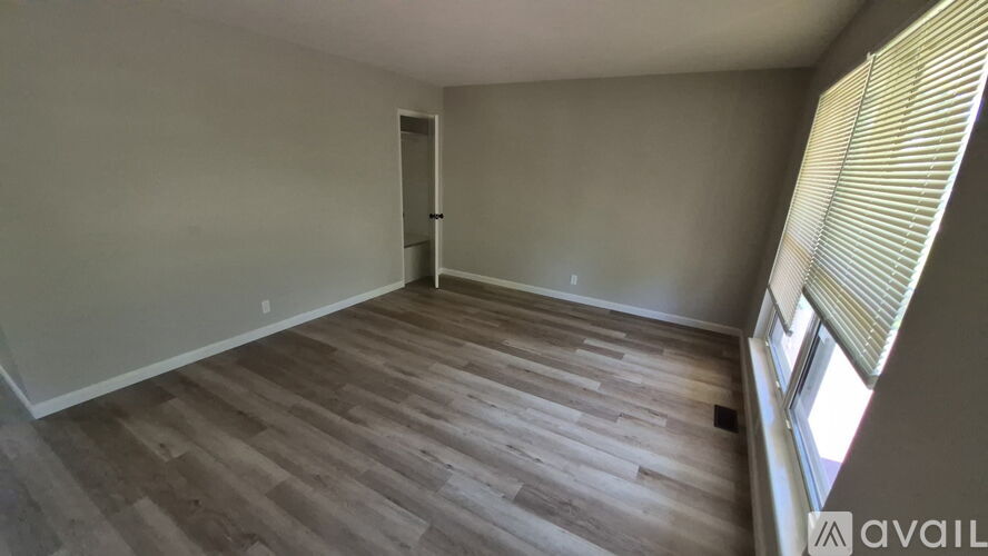 A room with wooden flooring and a window with blinds.