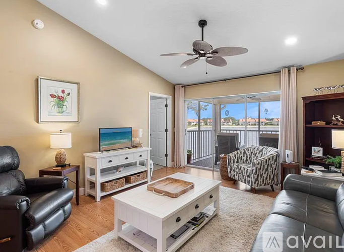 A living room with a black leather couch, a white coffee table, and a ceiling fan.