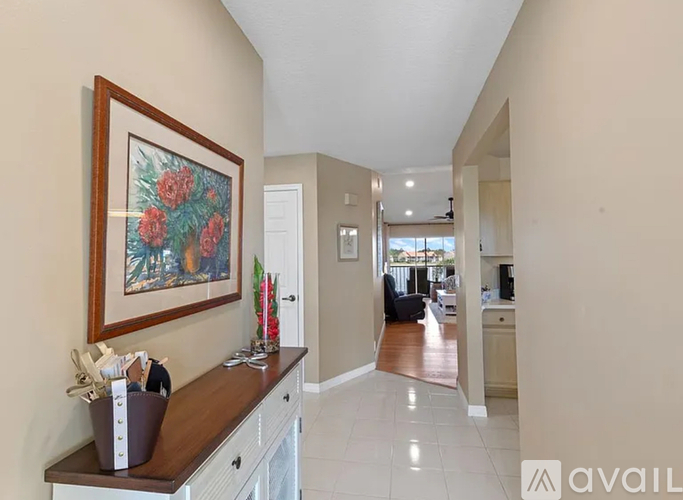 A hallway with a painting on the wall and a counter with a vase on it.
