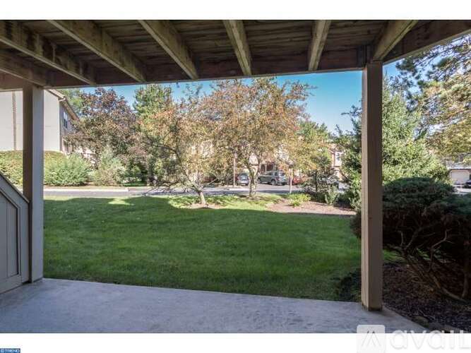 A view from a covered patio looking out to a green lawn and trees.