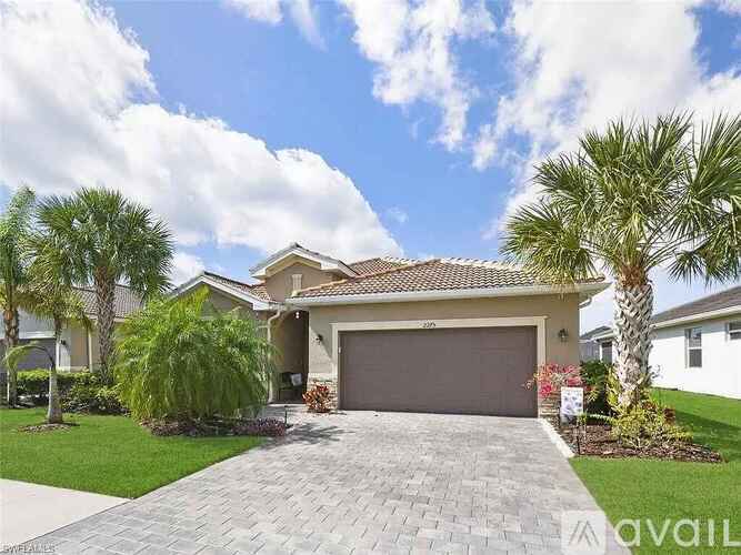 A house with a driveway and palm trees in front.