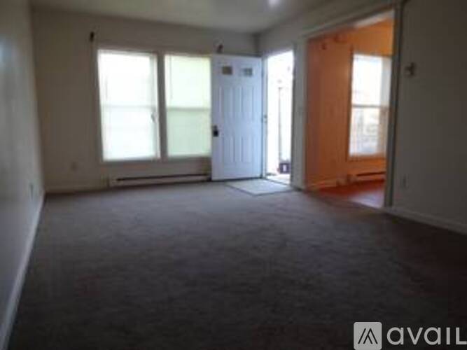 A room with a carpeted floor and a door on the right.