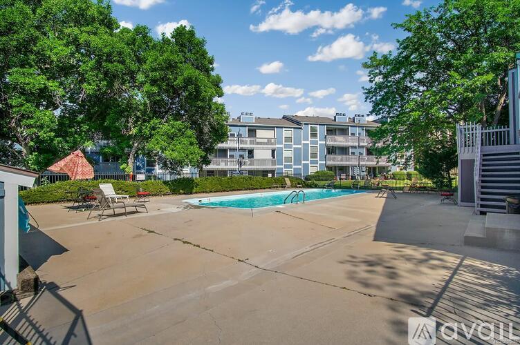 A swimming pool surrounded by trees and a building in the background.