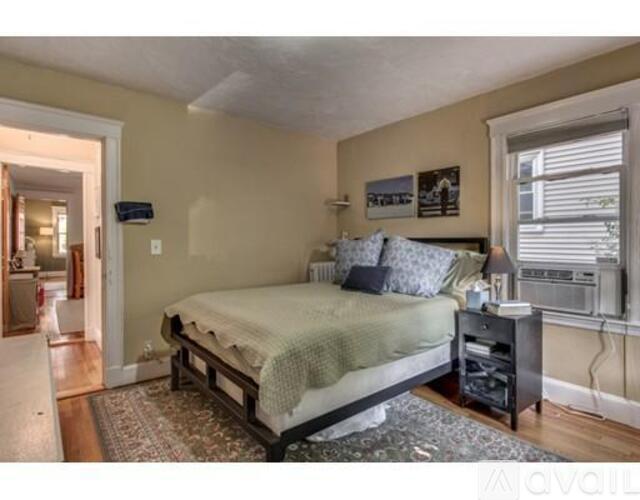 A bedroom with a bed, nightstand, and a window with blinds.