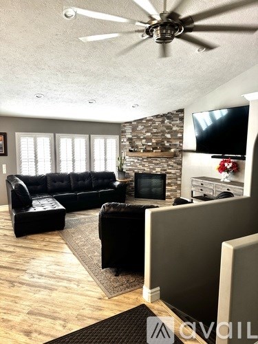 A living room with a black couch and a television on the wall.