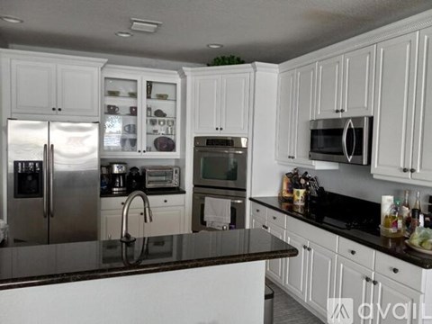 A kitchen with white cabinets and a black countertop.