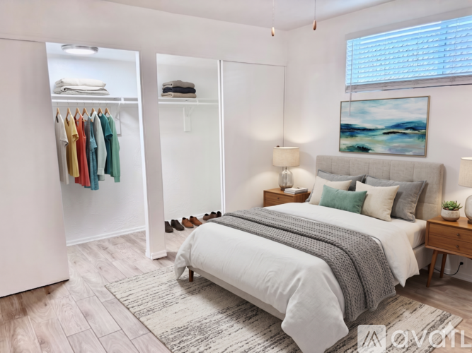 A bedroom with a bed, two lamps, a painting, and a wardrobe.