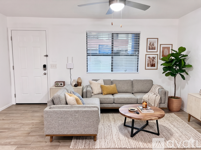A living room with a grey couch, a wooden coffee table, and a plant.