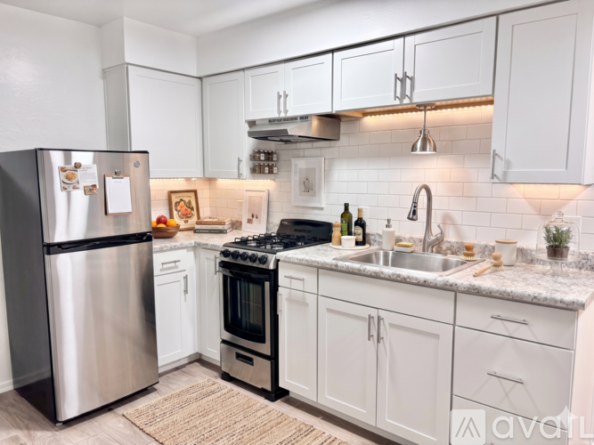 A kitchen with white cabinets and a stainless steel refrigerator.