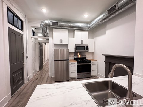 A kitchen with a stainless steel sink and a refrigerator.