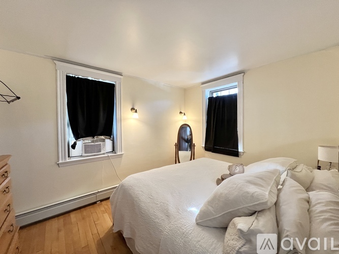 A bedroom with a large bed and two windows.
