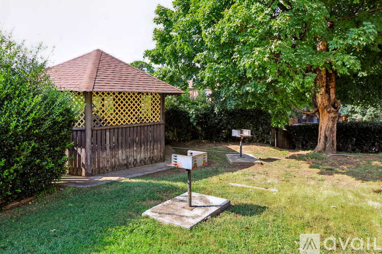 A gazebo with a yellow lattice top is surrounded by greenery.