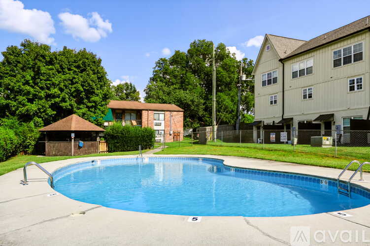 A swimming pool in front of a building with a tree in the background.