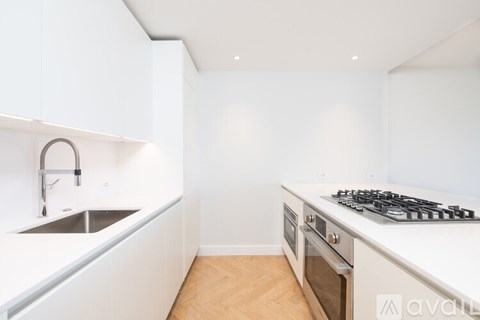 A kitchen with a stove, sink, and cabinets.