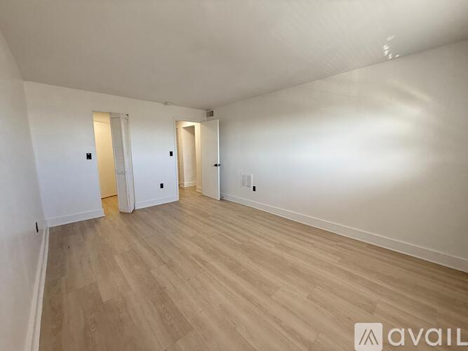A spacious room with wooden flooring and white walls.