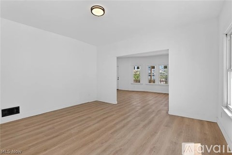 A spacious room with wooden flooring and white walls.