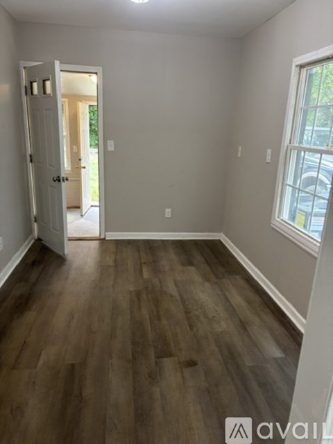 A room with wooden flooring and a doorway leading to another room.