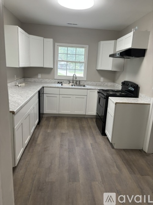 A kitchen with white cabinets and a black stove top oven.