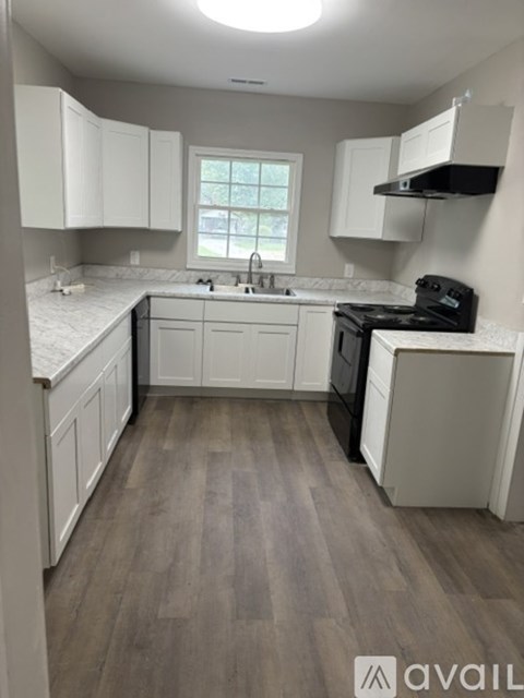 A kitchen with white cabinets and a black stove top oven.