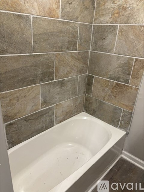A bathroom with a tiled wall and a white bathtub.