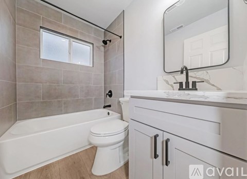 A bathroom with a white tub, toilet, and sink.