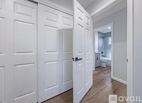 A hallway with white doors leading to a bathroom.