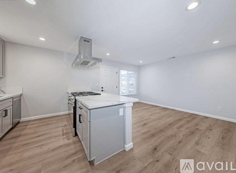 A kitchen with a white stove top oven and wooden flooring.
