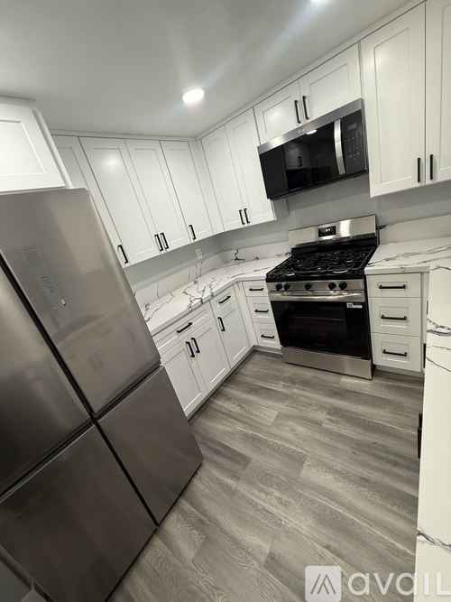 A kitchen with white cabinets and a stainless steel refrigerator.