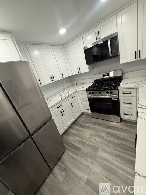 A kitchen with white cabinets and a stainless steel refrigerator.
