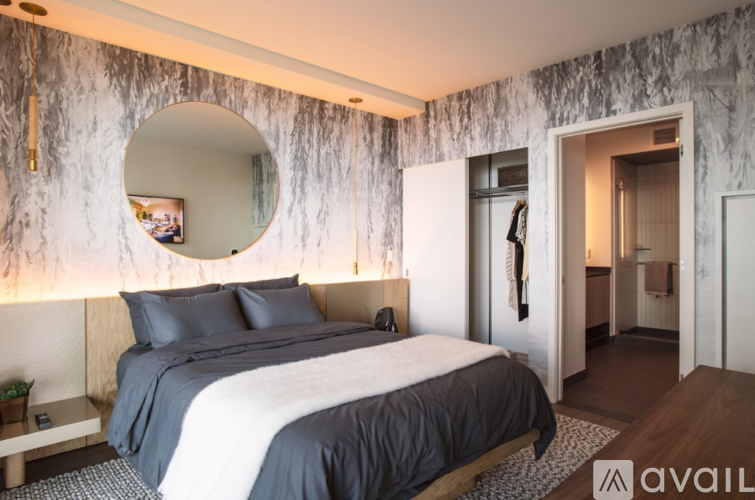 A bedroom with a large bed and a round mirror on the wall.
