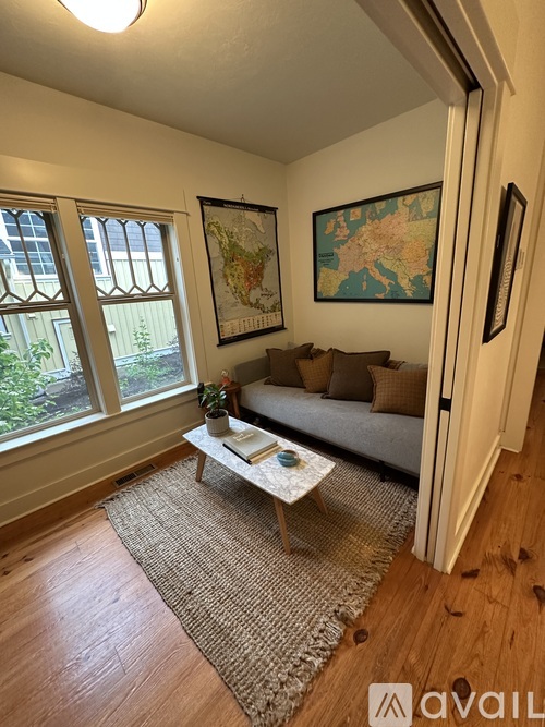 A living room with a couch, coffee table, and two maps on the wall.