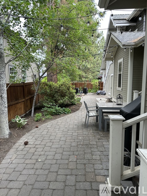 A patio with a table and chairs is surrounded by a fence and trees.