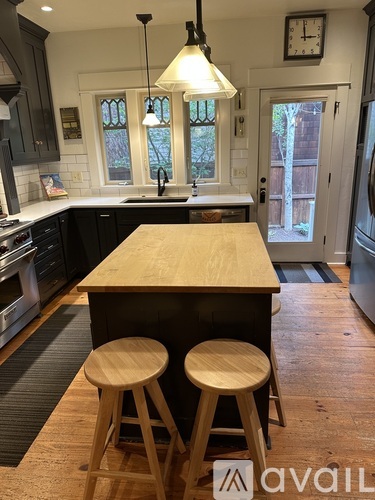 A kitchen with a wooden island and two stools.