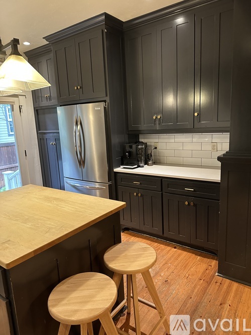 A kitchen with black cabinets and a wooden island.